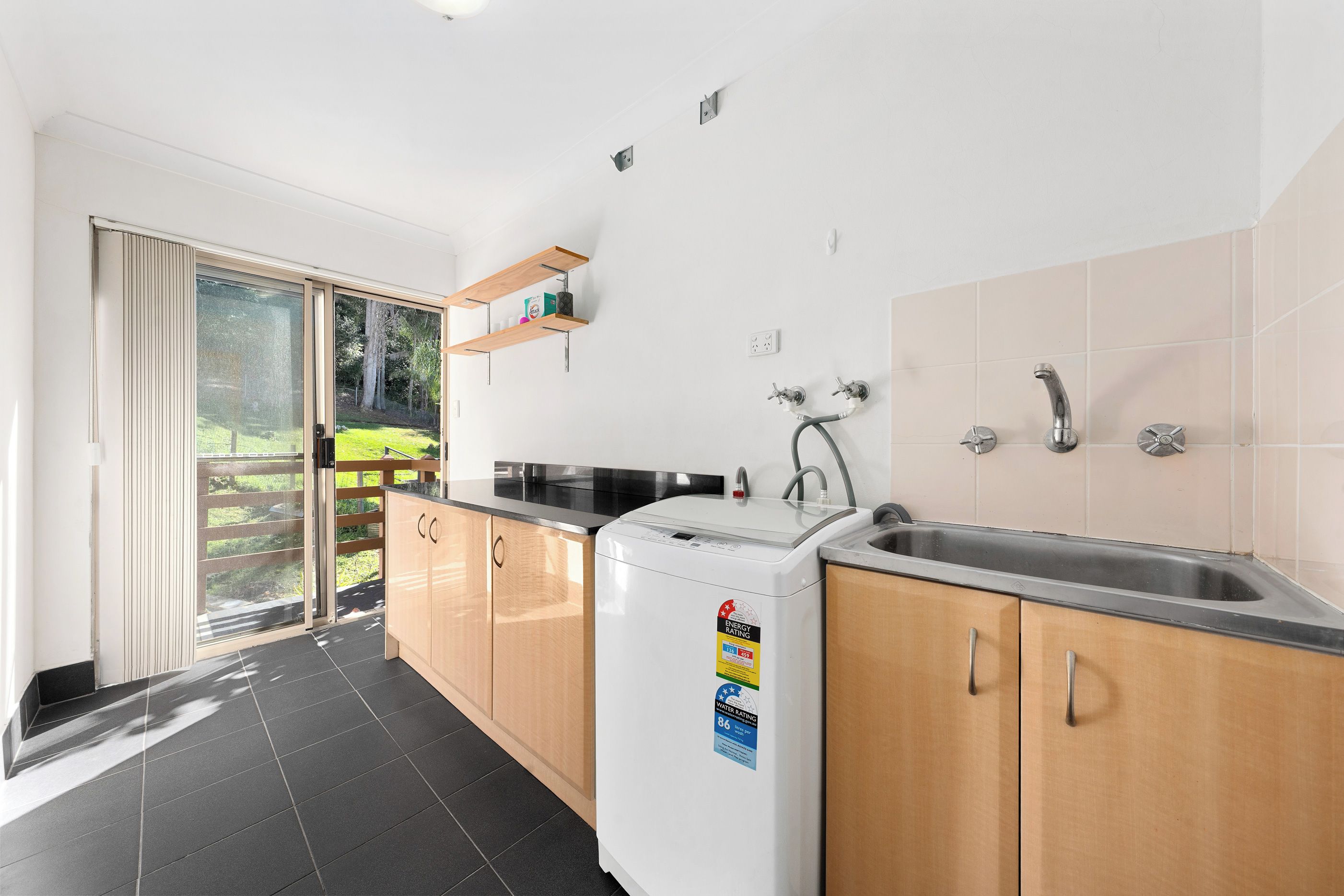 A modern kitchen with a built-in washing machine, a sink, and a sliding glass door leading to a balcony.