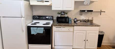 A compact kitchen with a refrigerator, stove, microwave, and dishwasher.