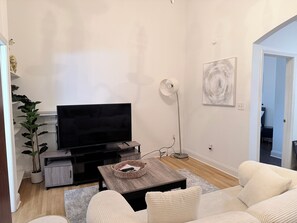 A living room with a flat-screen TV, a coffee table, a floor lamp, and a sofa. - Perfect 1-bedroom apartment with AC in beautiful Doraville (Doraville)