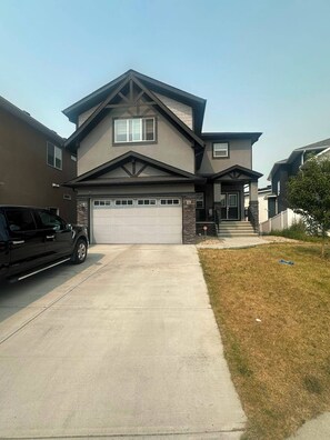 A two-story house with a garage, a driveway, and a lawn.