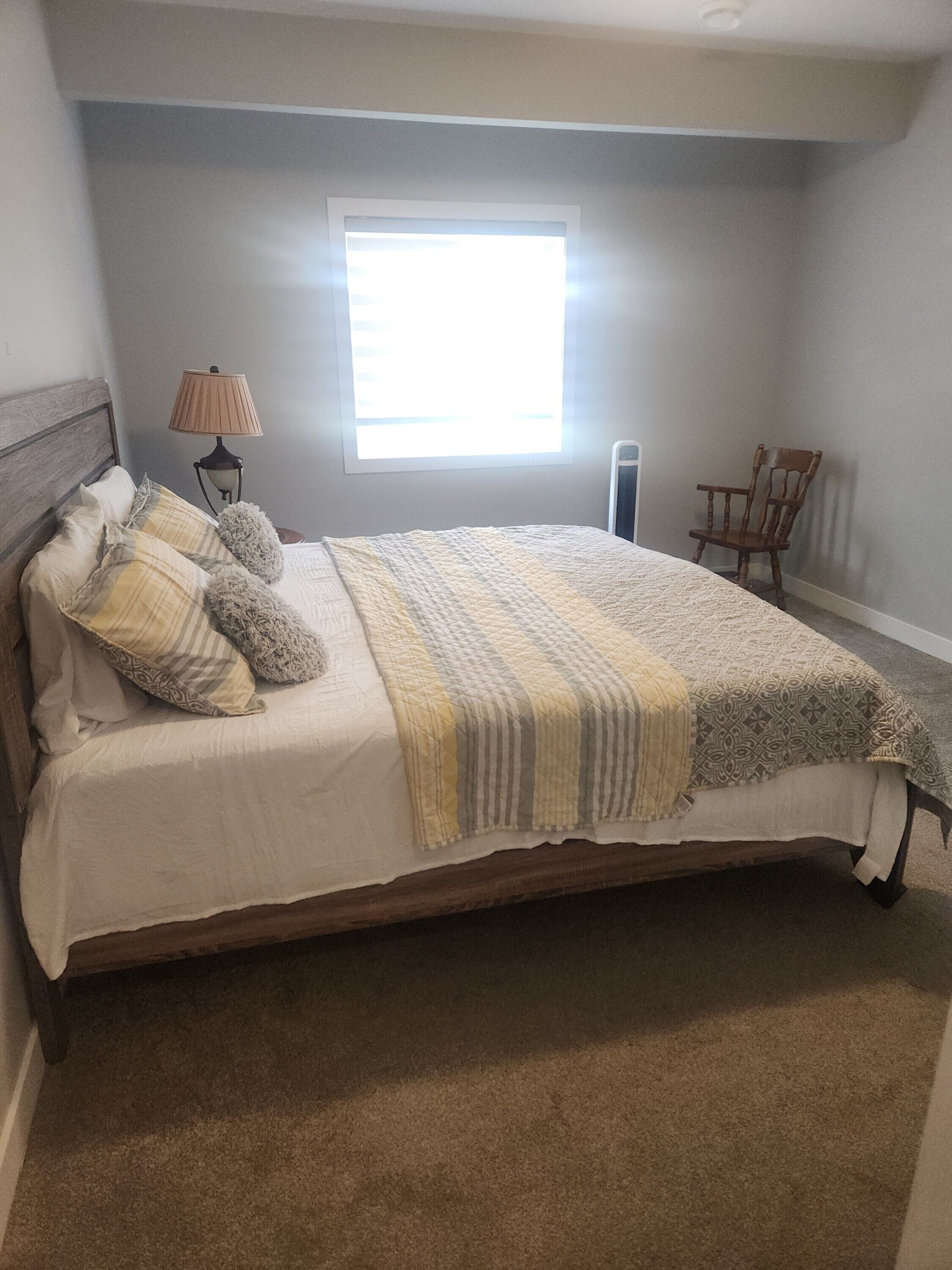 Une chambre à coucher avec un lit, une fenêtre, une lampe et une chaise.
