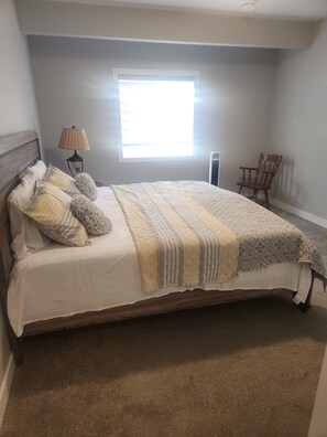 A bedroom with a bed, a window, a lamp, and a chair.