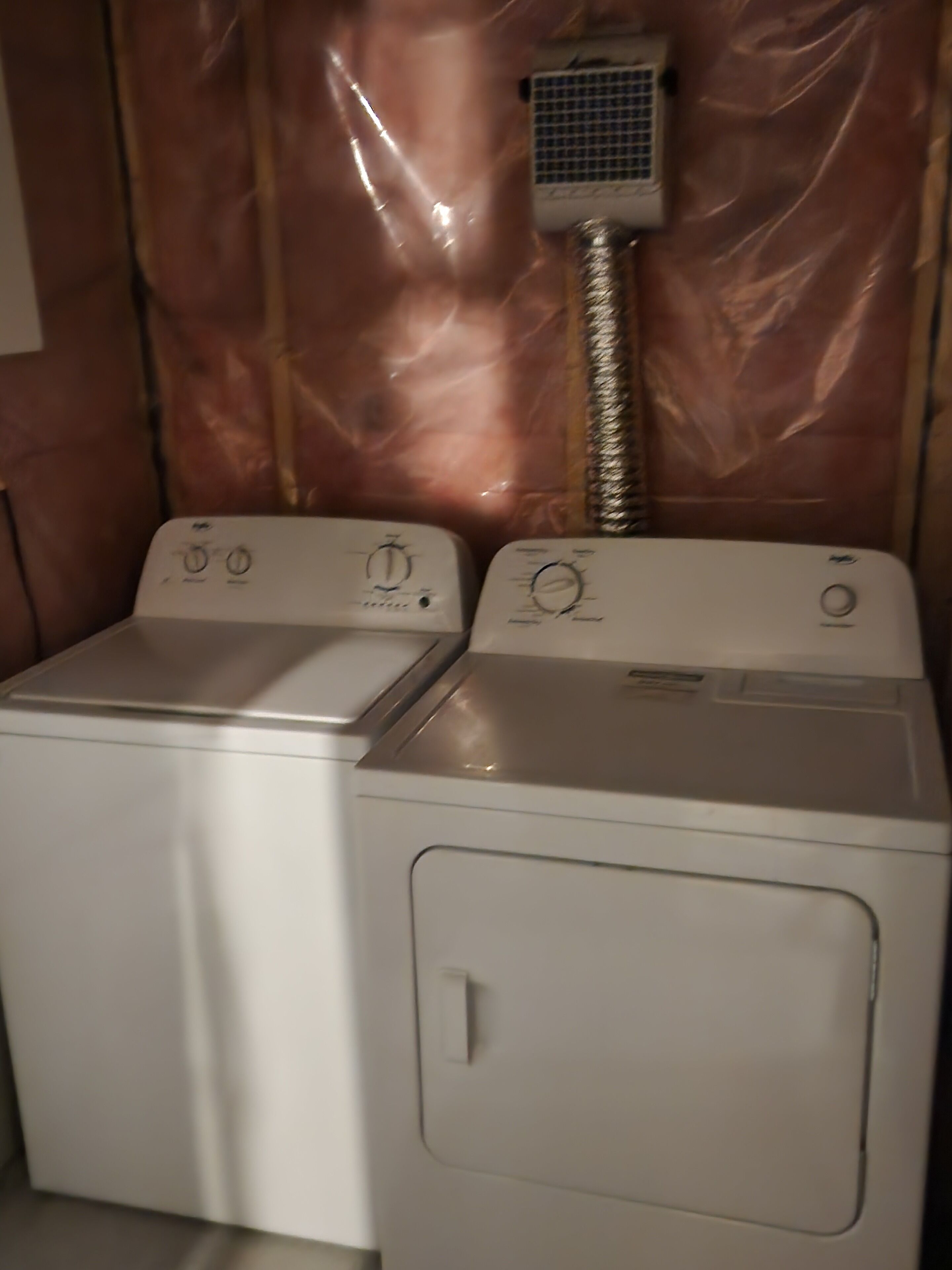 A laundry room with two front-loading washing machines and a dryer.