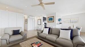 Ein modernes Wohnzimmer mit zwei Sofas, einem Couchtisch und einem Deckenventilator.