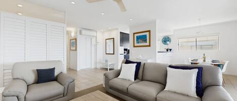 A modern living room with two sofas, a coffee table, and a ceiling fan.
