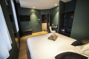 Una habitación de hotel con cama, escritorio, silla, armario y televisión.