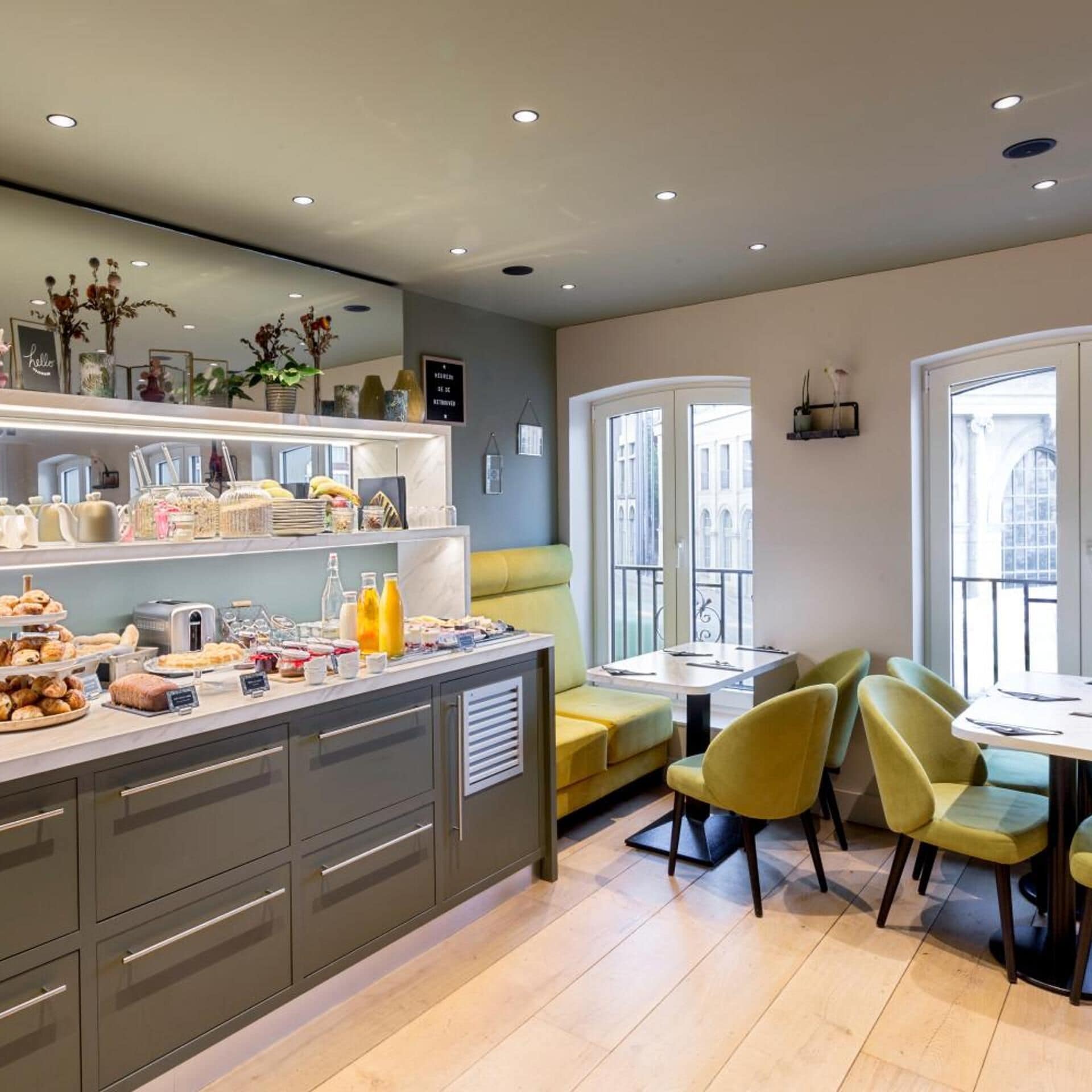 Een moderne keuken met een ontbijtbalk, een zithoek met een tafel en stoelen, en grote ramen voor veel daglicht.