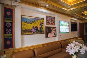 Un área de recepción con un sofá marrón, una obra de arte en la pared y un arreglo floral.