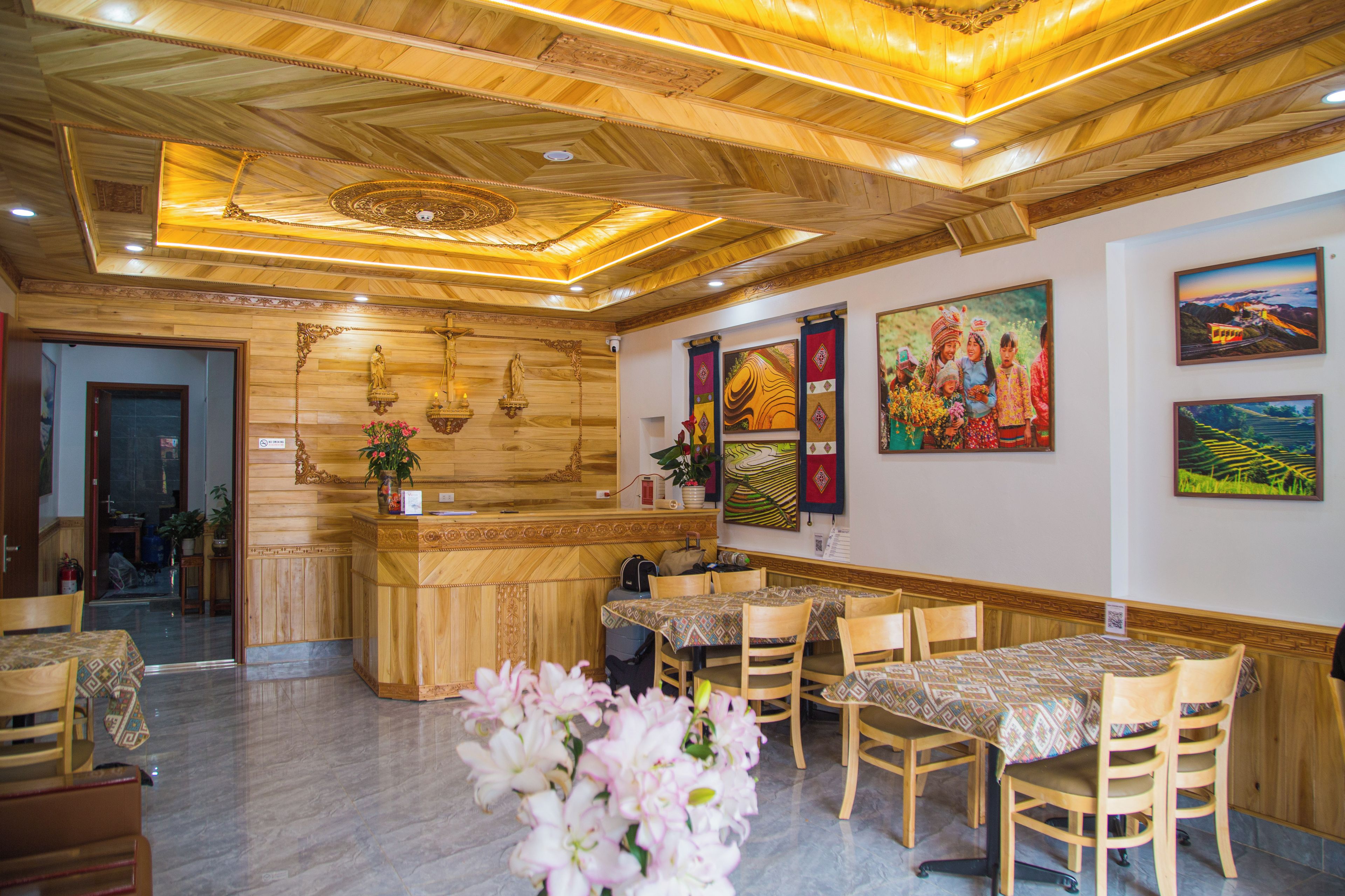 A hotel lobby with wooden paneling, a reception desk, and a dining area with tables and chairs.