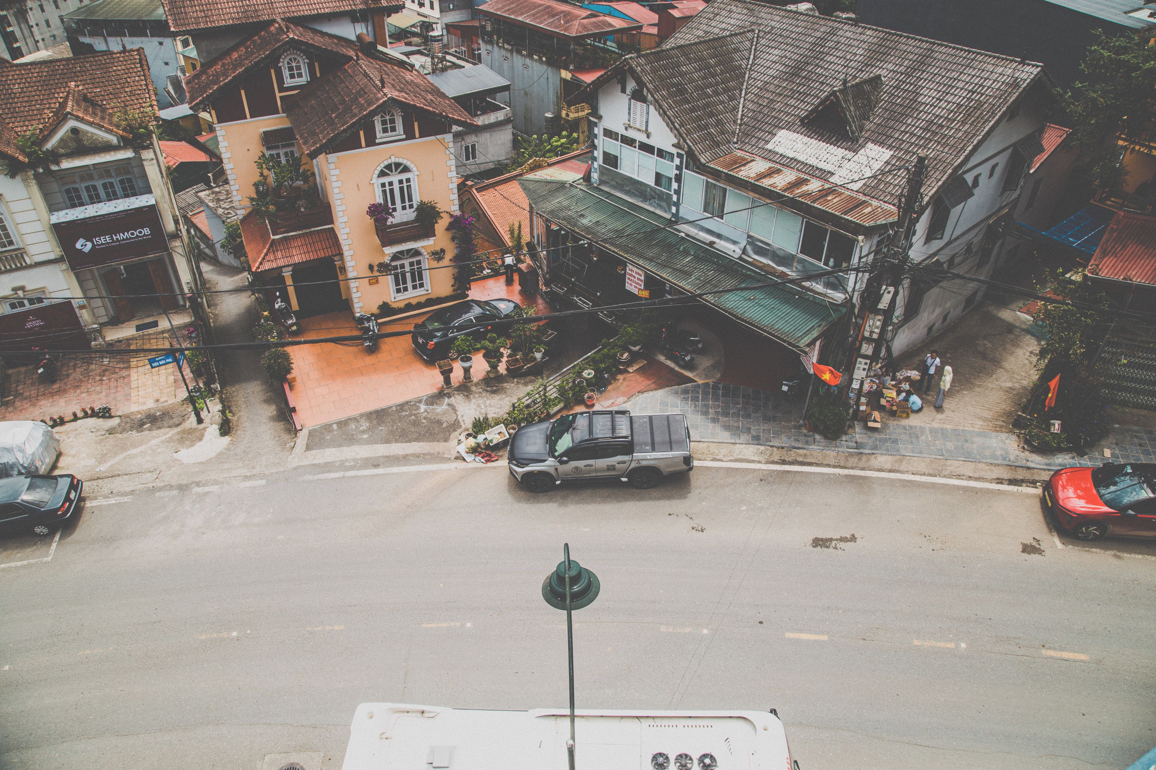 A street view with buildings, a parked car, and a pedestrian crossing.