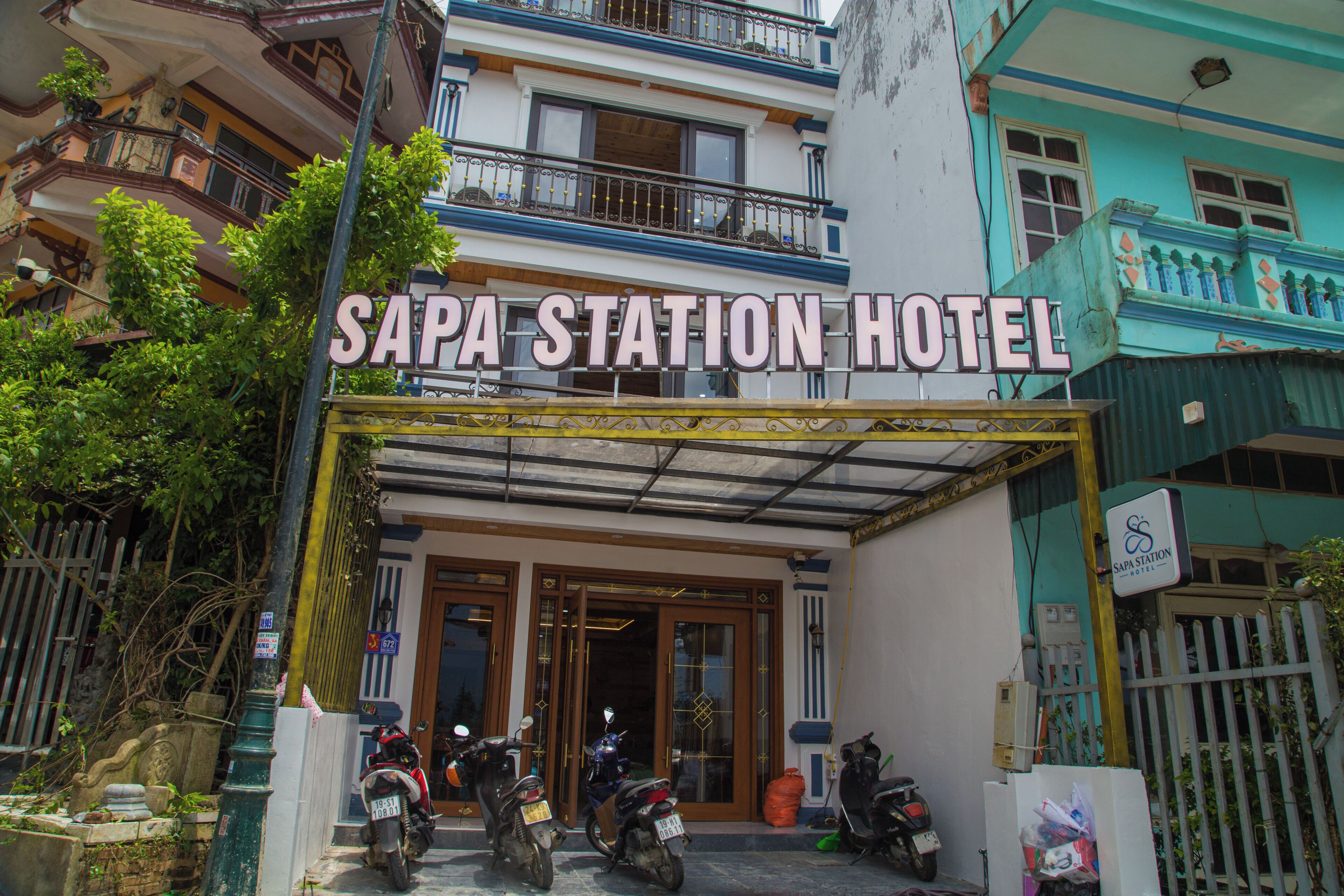 Entrada do Sapa Station Hotel, com acesso coberto e placa acima.
