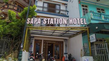 Entrada do Sapa Station Hotel, com acesso coberto e placa acima.
