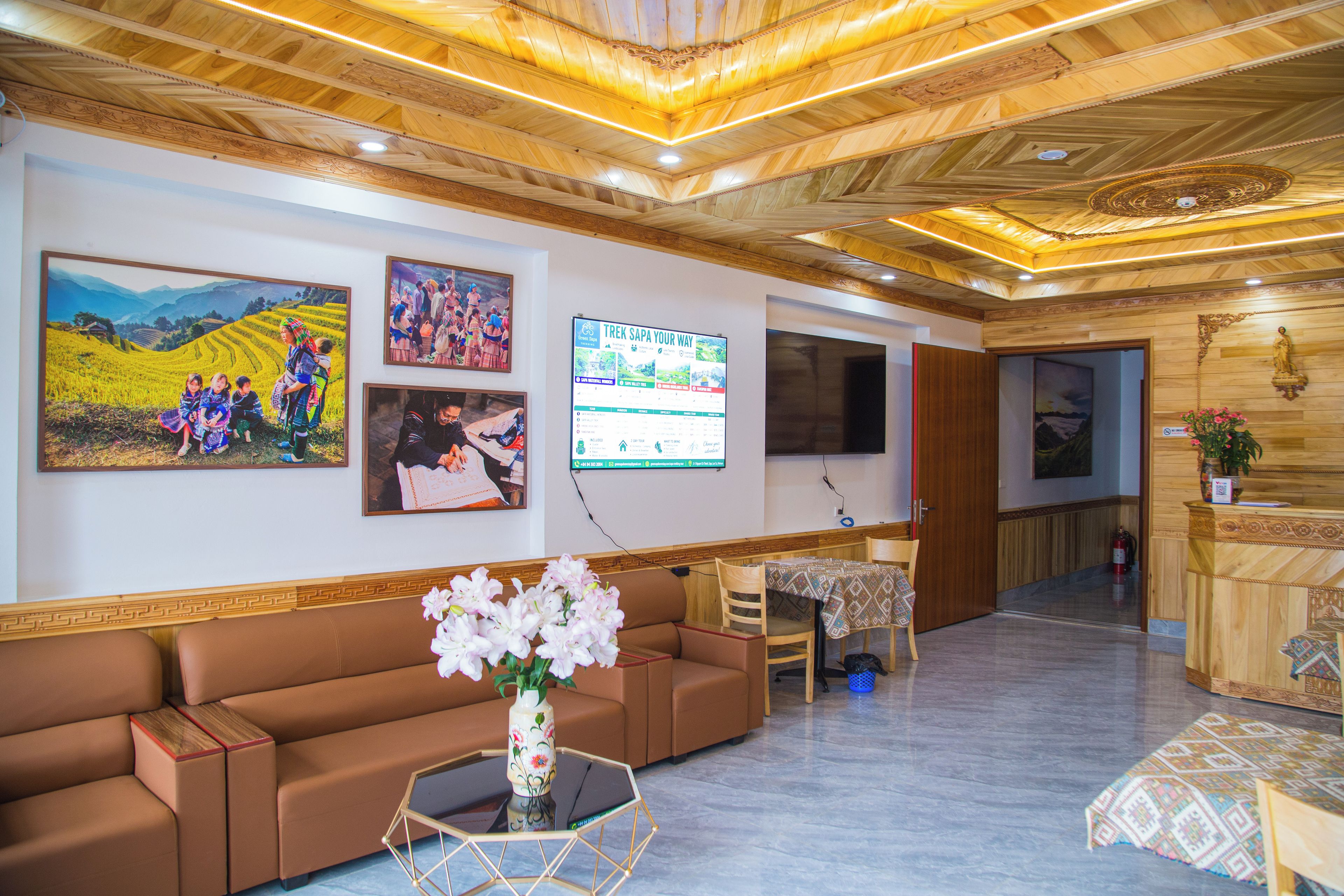 Un vestíbulo de hotel con techo de madera, un mostrador de recepción, un sofá y obras de arte colgadas en la pared.
