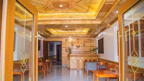 A hotel lobby with wooden flooring, a reception desk, and seating arrangements.