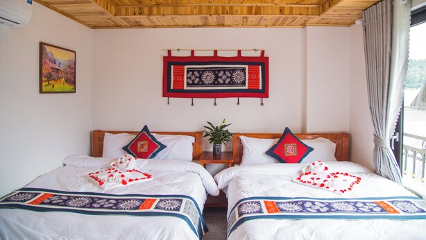 Habitació d'hotel amb dos llits, sostre de fusta, un quadre a la paret i una finestra amb cortines.