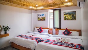 A hotel room with two beds, a wooden ceiling, and two landscape paintings.