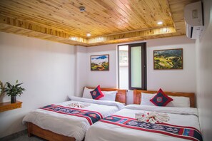 Habitación de hotel con dos camas, techo de madera y dos cuadros de paisajes.