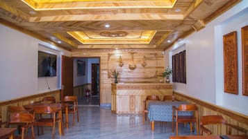 A hotel lobby with wooden paneling, a reception desk, and seating arrangements.