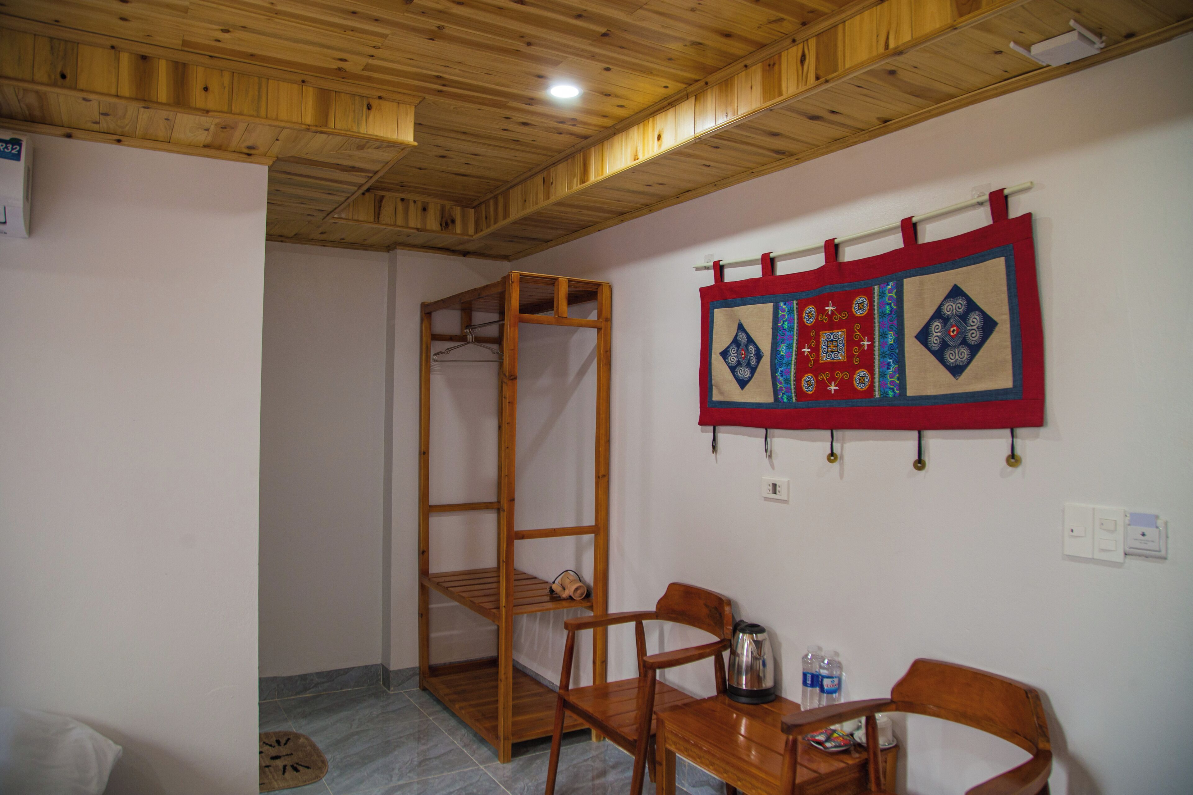 A room with a wooden ceiling, a wooden bunk bed, a table with chairs, and a decorative wall hanging.