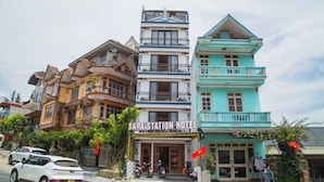 A hotel with a sign reading 'SAPA STATION HOTEL' in front of a multi-story building with balconies and a street view.
