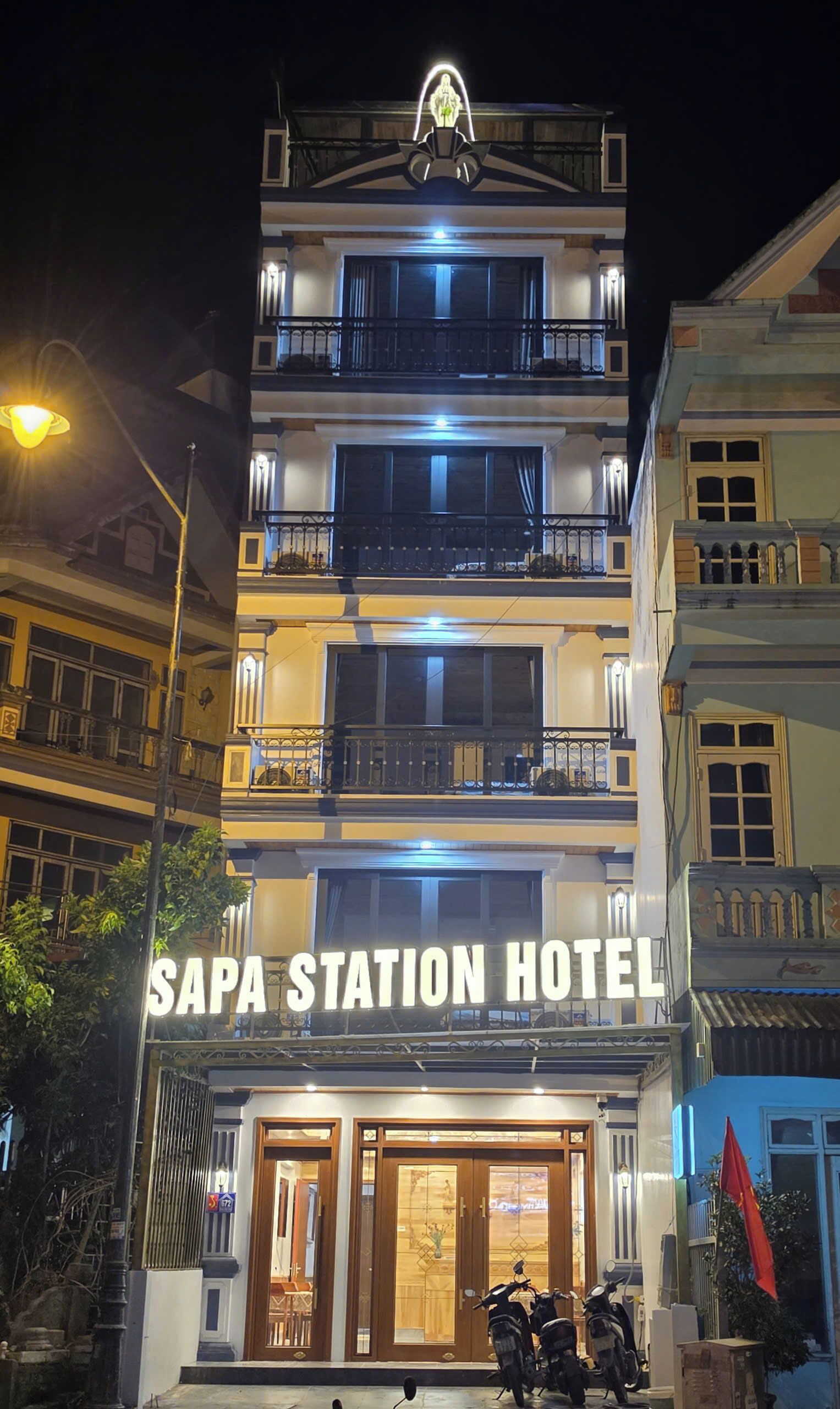 Un edificio de varios pisos con un letrero que dice 'SAPA STATION HOTEL'.