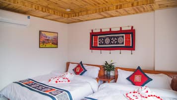 A hotel room with two beds, a wooden ceiling, a painting, and a decorative wall hanging.