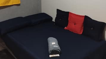 A room with a bed, a shelf with board games, and a yellow curtain.