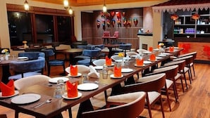 A restaurant with multiple dining tables, chairs, and a bar area. - Udaan Alpine Resort & Chongeytar (Gangtok)