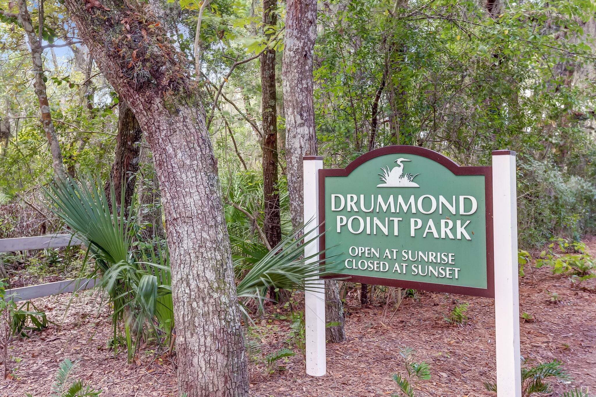 A sign for Drummond Point Park with a wooden fence and trees in the background.