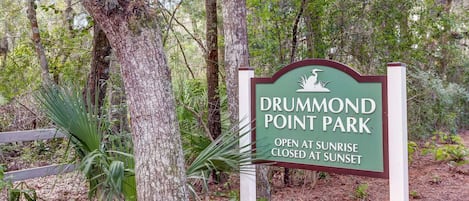 Un panneau indiquant l’entrée du parc Drummond Point, avec une clôture en bois et des arbres en arrière-plan.