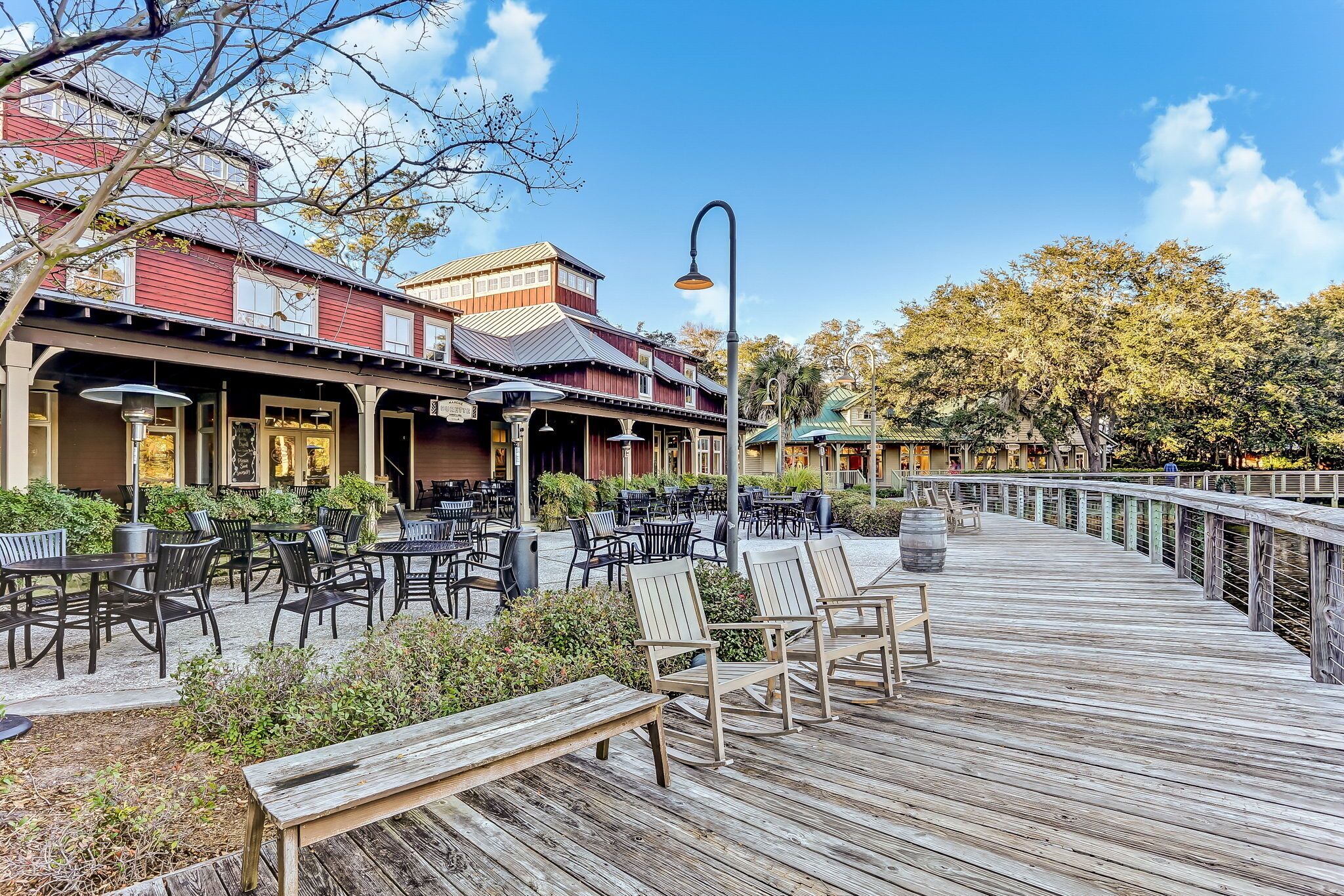 A wooden deck with outdoor seating, a covered patio area, and a building with a red facade.