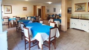 A dining area with multiple tables, chairs, and a buffet counter. - Il Gabbiano Hotel (Trinità d'Agultu e Vignola)