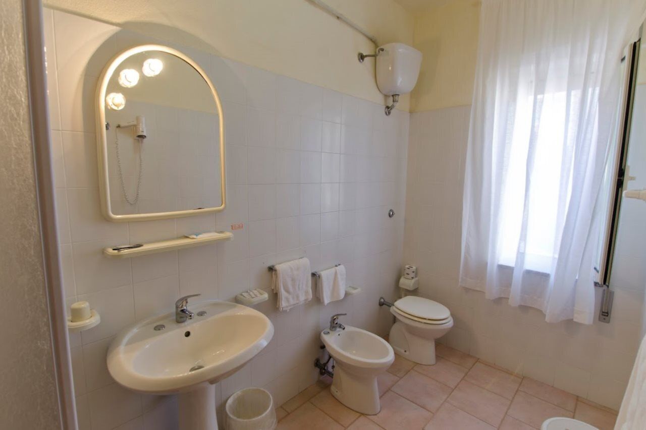 A bathroom with a sink, bidet, toilet, and a mirror with lights.