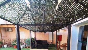 A covered patio area with artificial grass, a wooden table, and potted plants. - Il Gabbiano Hotel (Trinità d'Agultu e Vignola)