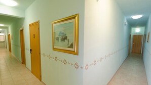 A corridor with doors on both sides, a framed picture on the wall, and a patterned border along the floor. - Il Gabbiano Hotel (Trinità d'Agultu e Vignola)