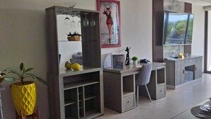 Une cuisine moderne dotée d’appareils électroménagers intégrés, un coin repas avec une table dressée pour quatre personnes, et une grande fenêtre offrant une vue sur les palmiers.
