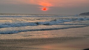 Un coucher de soleil sur une plage, avec des vagues.