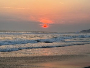 Ein Sonnenuntergang über einem Strand mit Wellen.