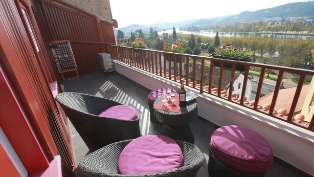 A balcony with wicker furniture and a view of a river and hills. - Casas Da Alegria (Coimbra)