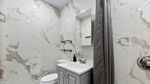 A bathroom with a white toilet, a sink with a mirror above it, and a shower area.