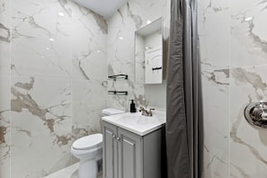 A bathroom with a white toilet, a sink with a mirror above it, and a shower area.