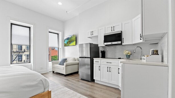 A modern kitchen with white cabinets, stainless steel appliances, and a large window.