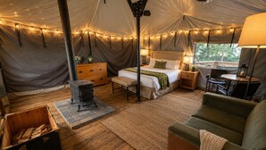 Alojamiento con carpa que incluye cama, zona de estar y una pequeña mesa.