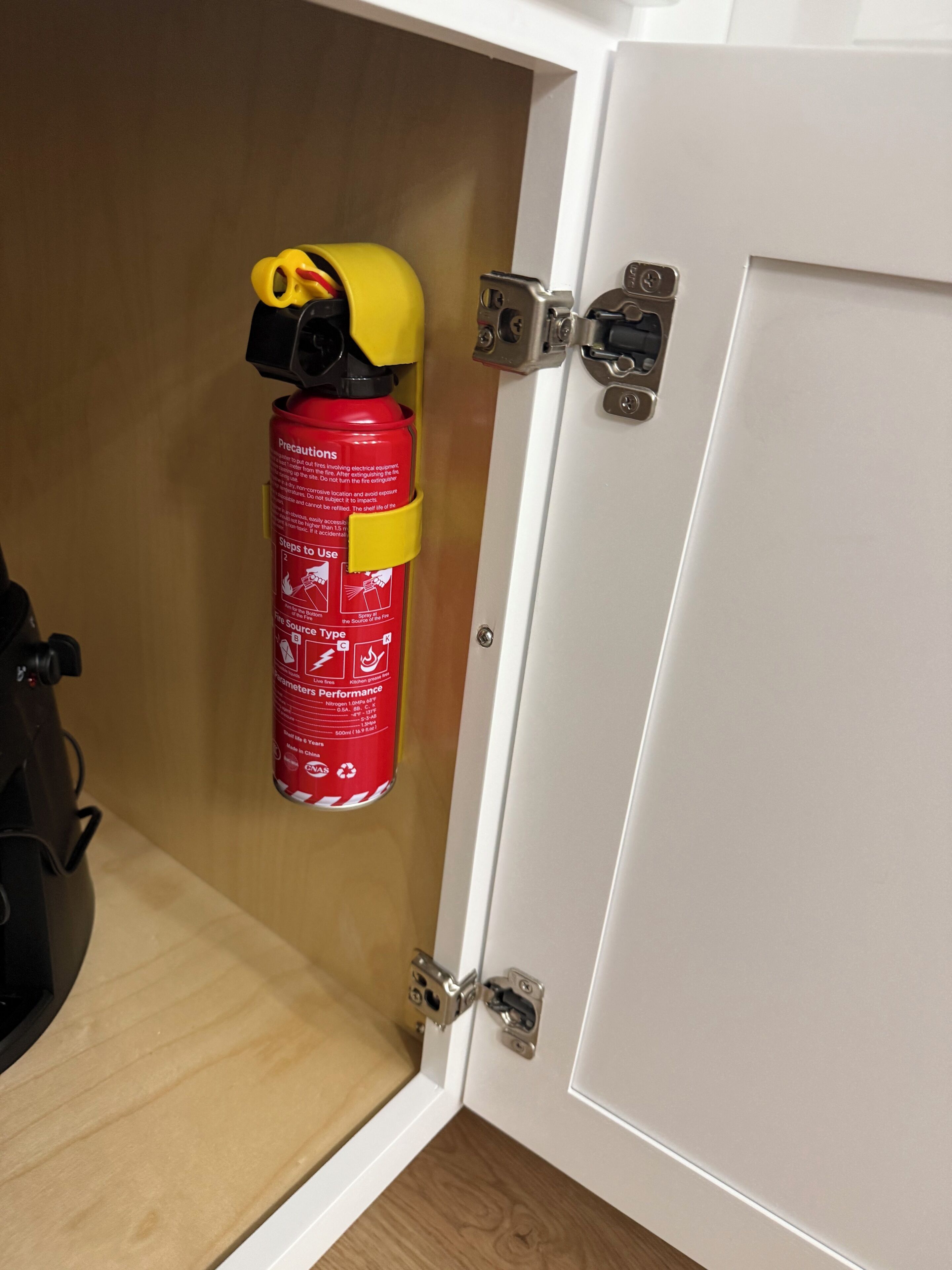 A fire extinguisher mounted on a wall next to a door with a metal latch.