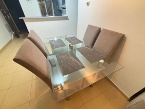 A glass-top dining table with four chairs, a window above, and a tiled floor. - Apartment Espana On Mar Menor Golf Resort (Torre Pacheco)