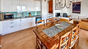 A kitchen with white cabinets, a microwave, a stove, and a dining area with a wooden table and chairs. - Nice home in MONS with private swimming pool, can be inside or outside (MONS)