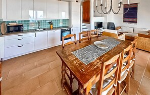 Eine Küche mit weißen Schränken, einer Mikrowelle, einem Herd und einem Essbereich mit Holztisch und Stühlen.
