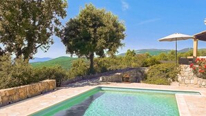 A swimming pool with a stone wall and a view of green hills. - Nice home in MONS with private swimming pool, can be inside or outside (MONS)