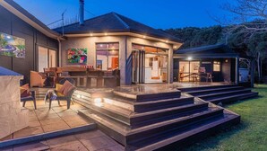 Una casa moderna con patio coperto, posti a sedere all'aperto e una scala che conduce all'ingresso.