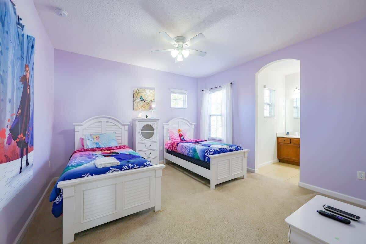 A bedroom with two beds, a ceiling fan, and a small table with a remote control.
